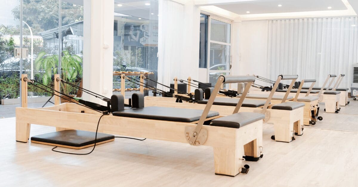 Modern Pilates reformers lined up in bright new studio space with natural light