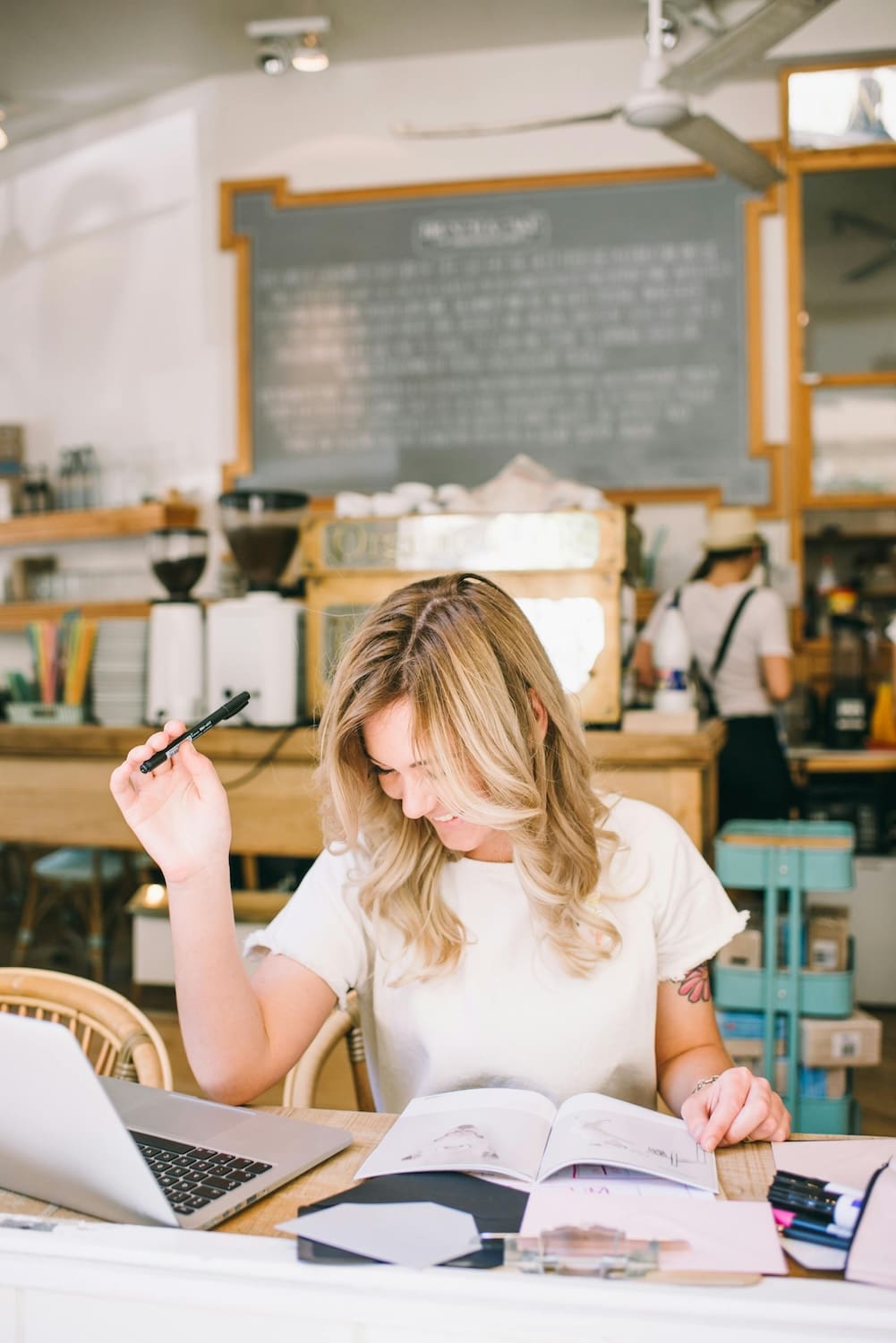 Woman working on editing a website template on her laptop computer in a colorful cafe.